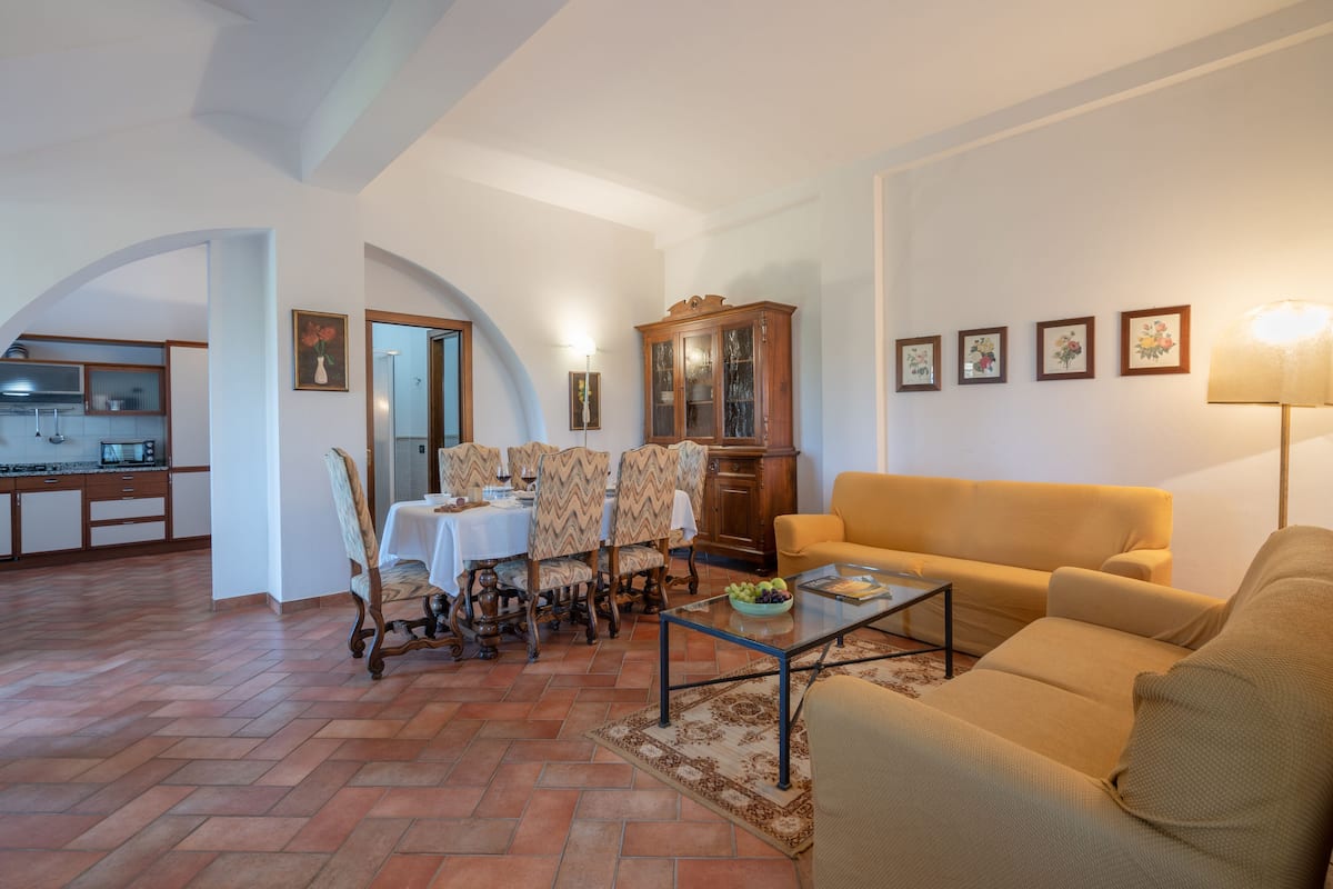 A living room with a sofa, coffee table, and dining area with chairs and a table.