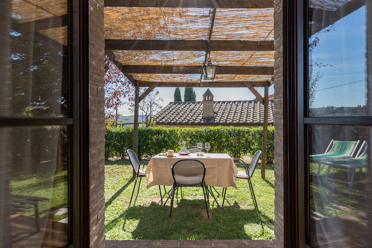 An outdoor patio with a table set for two, a chair, and a hanging lantern.