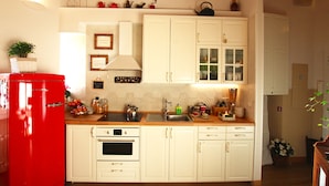 A kitchen with white cabinets, a red refrigerator, and various kitchen items on the counter. - Campanella3 (Rome)