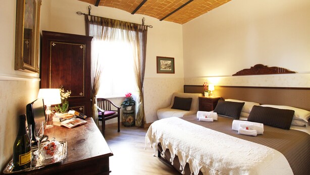 A hotel room with a bed, bedside table, lamp, and a window with curtains. - Campanella3 (Rome)