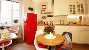 A kitchen with white cabinets, a red refrigerator, and a dining table with chairs. - Campanella3 (Rome)