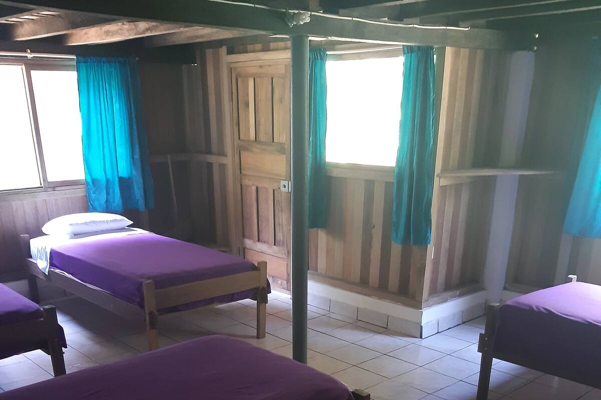 A room with four beds, wooden walls, and a tiled floor.