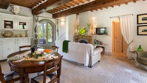 Un área de comedor con una mesa y sillas de madera, un sofá y un televisor en una sala de estar.