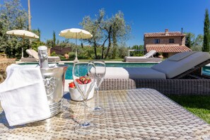 A poolside setting with a champagne bottle, two glasses, and a bowl of strawberries. - Villa Ligheia (Gambassi Terme)