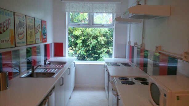 Una cocina con armarios blancos, microondas, fregadero y ventana con vistas al exterior.