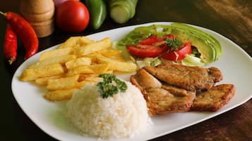 Un plato de comida con arroz, papas fritas, pollo a la parrilla y una ensalada.