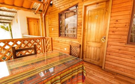 A wooden cabin with a dining table, chairs, and a window.