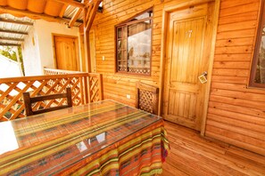 Una cabaña de madera con una mesa de comedor, sillas y un ventanal.