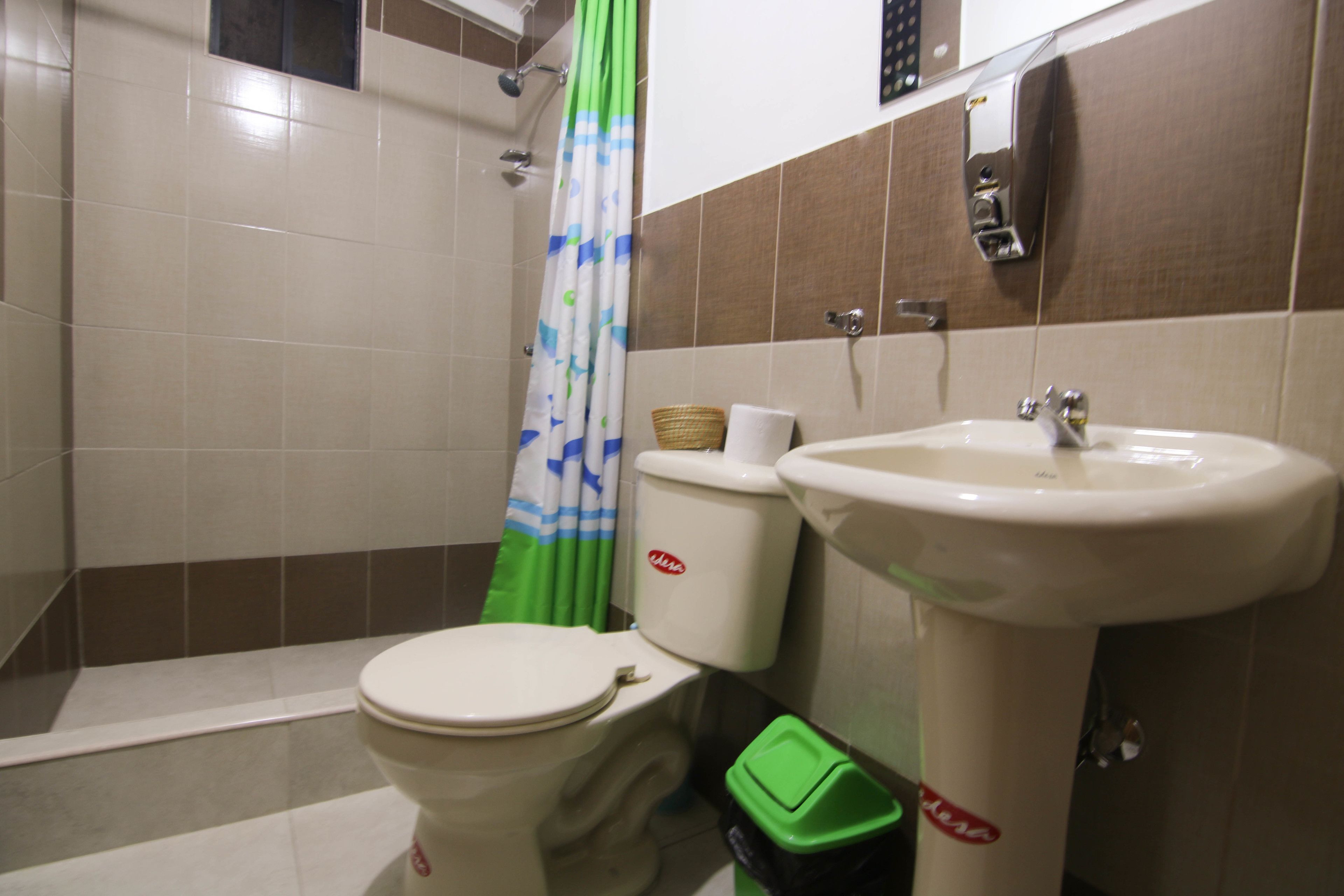 Baño con inodoro, lavabo y cortina de ducha.