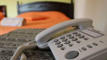 Un téléphone blanc est posé sur une couvre-lit à motifs dans une pièce dont la tête de lit est noire.