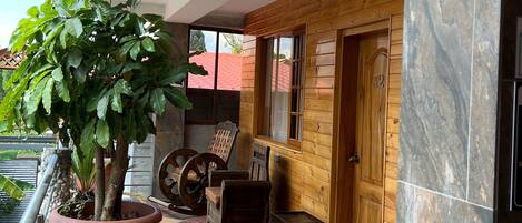 A wooden cabin with a checkered floor, a large potted tree, and a wooden door with the number 39.