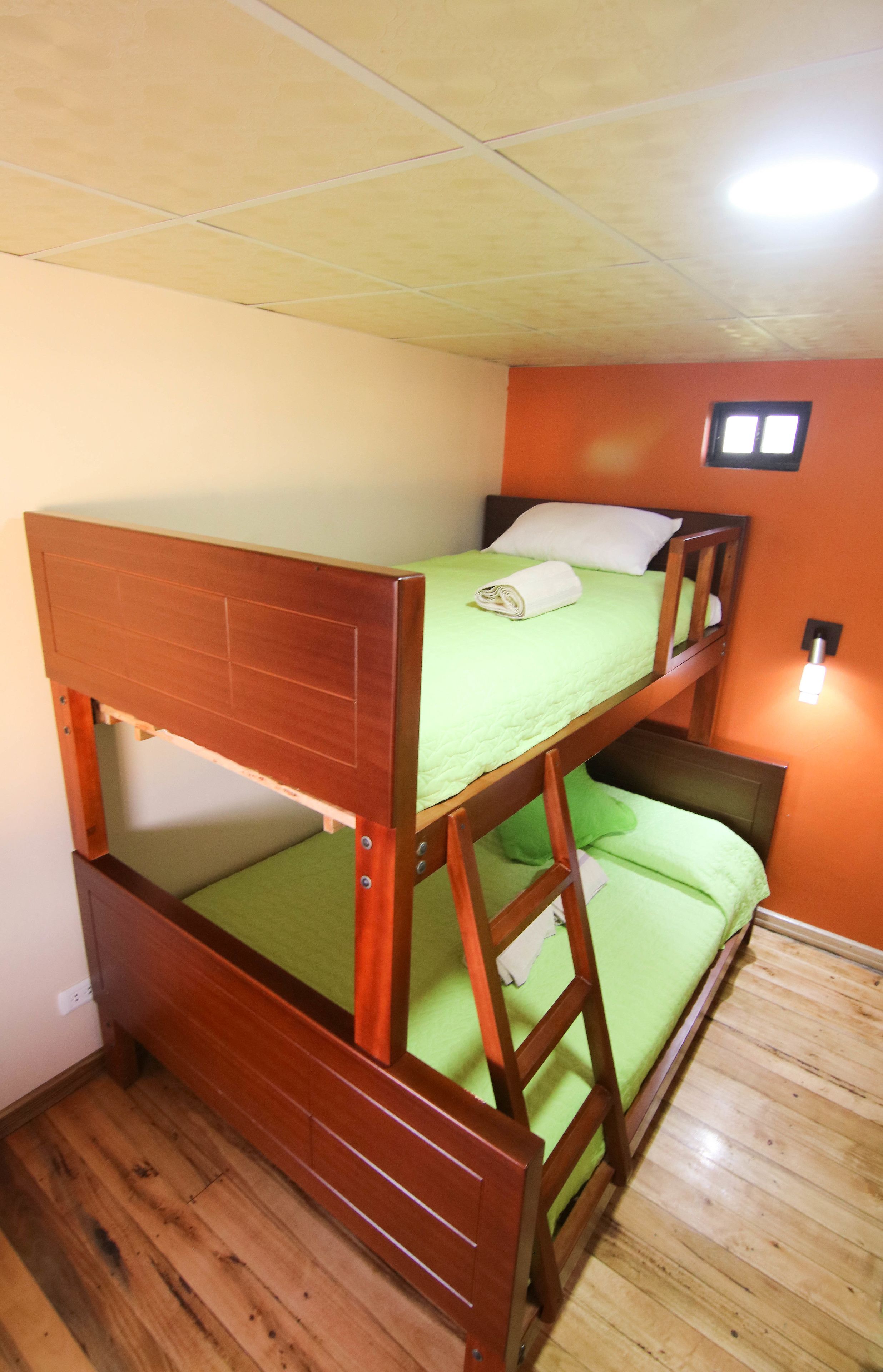 A bunk bed with green bedding and a wooden headboard.