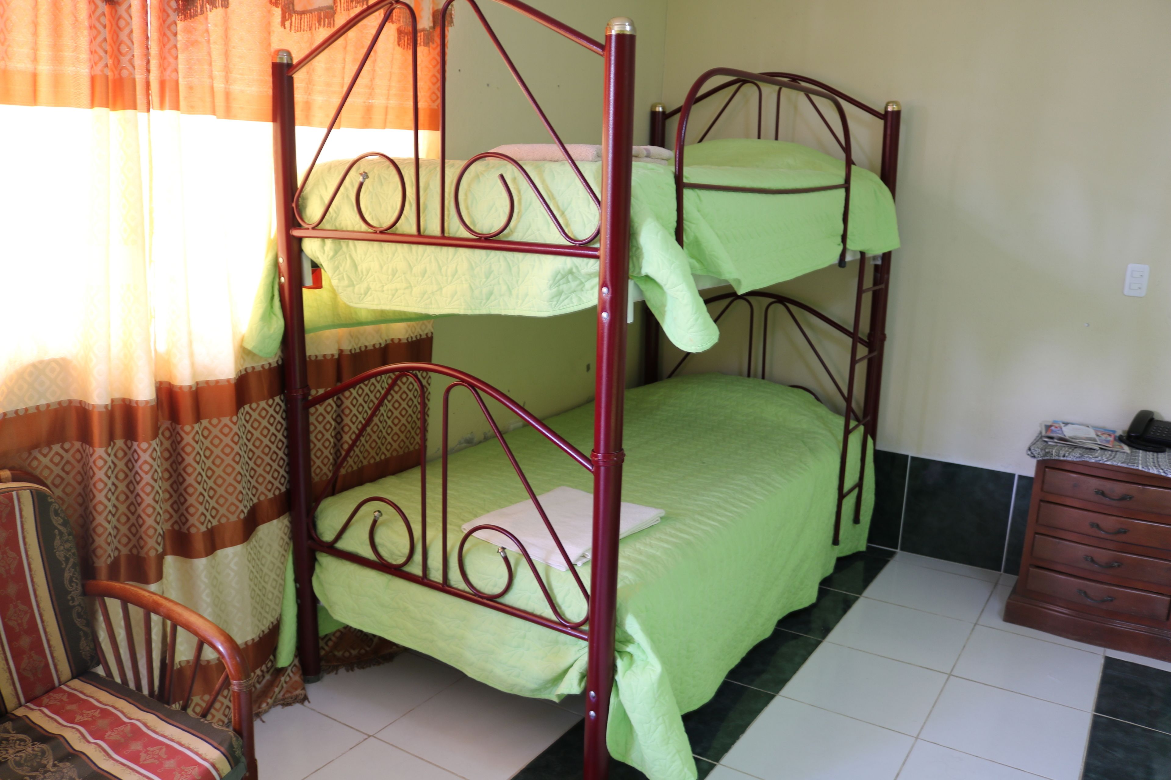 A bunk bed room with a chair and a dresser.