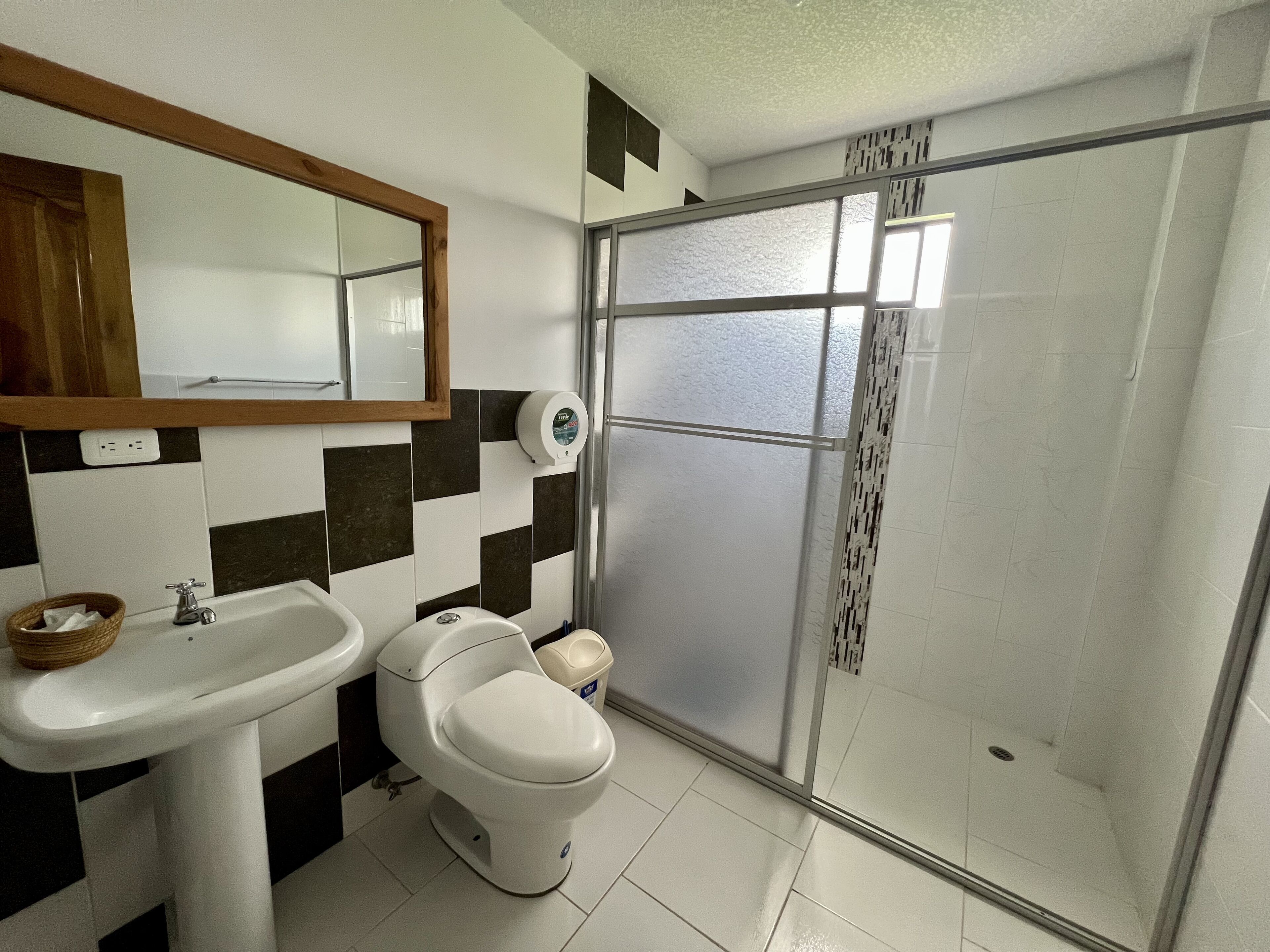 A bathroom with a white sink, a toilet, and a glass shower enclosure.