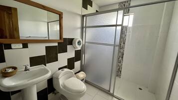 A bathroom with a white sink, a toilet, and a glass shower enclosure.