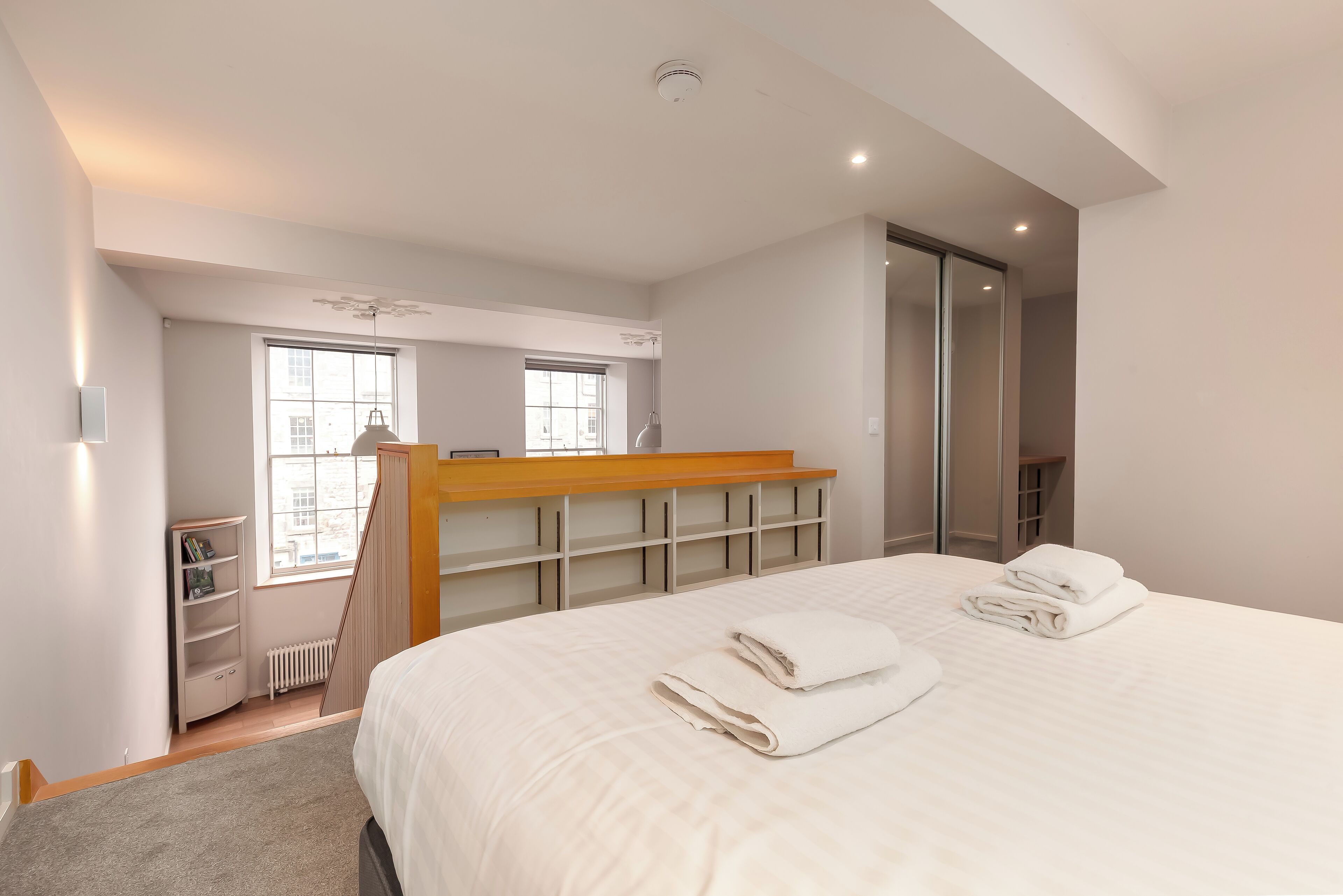 Ein Schlafzimmer mit einem großen Bett, einer hölzernen Bank, einem weißen Kleiderschrank und einem Fenster.