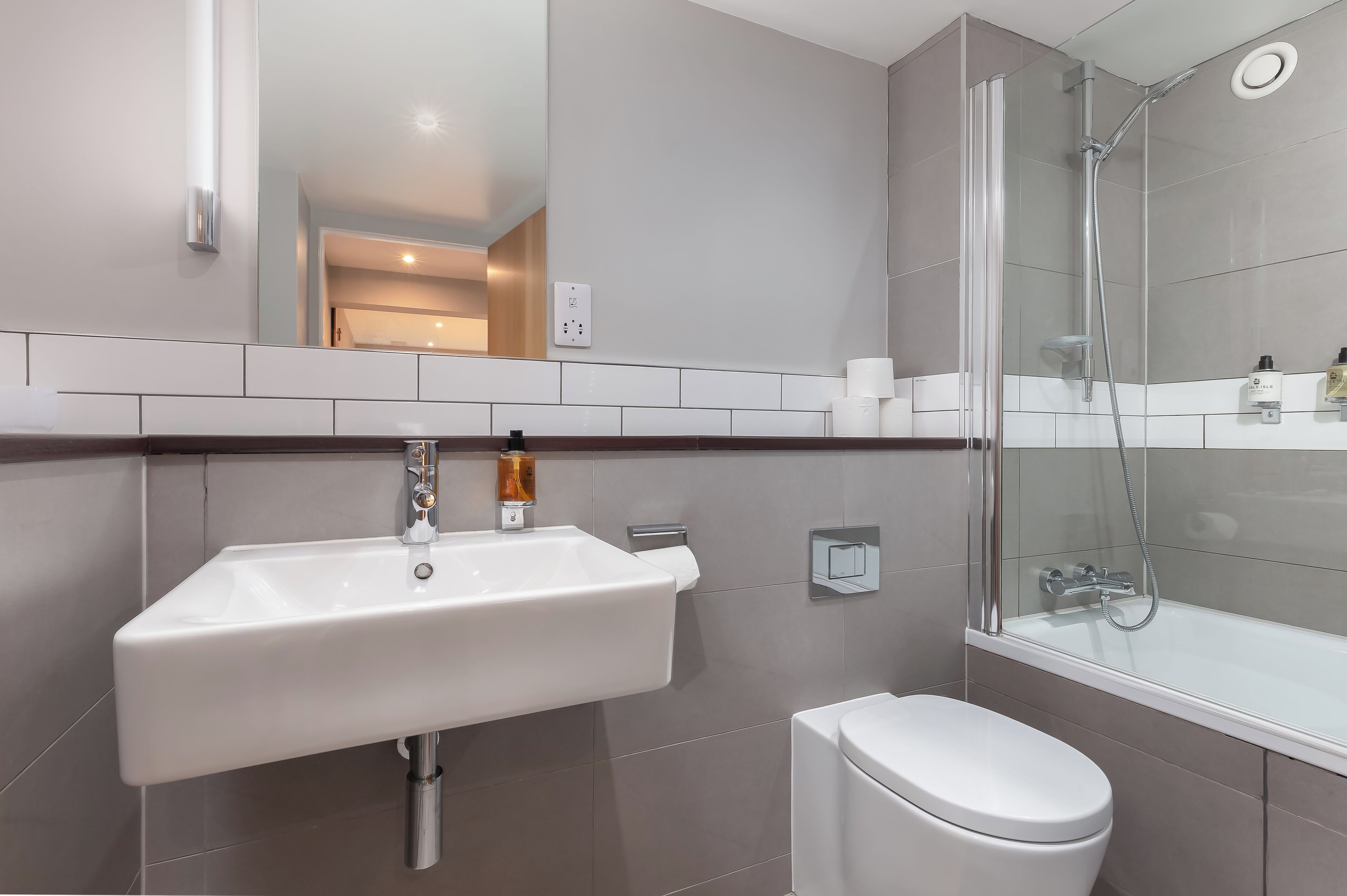 Casa de banho moderna com lavatório branco, sanita e cabine de duche com vidro.