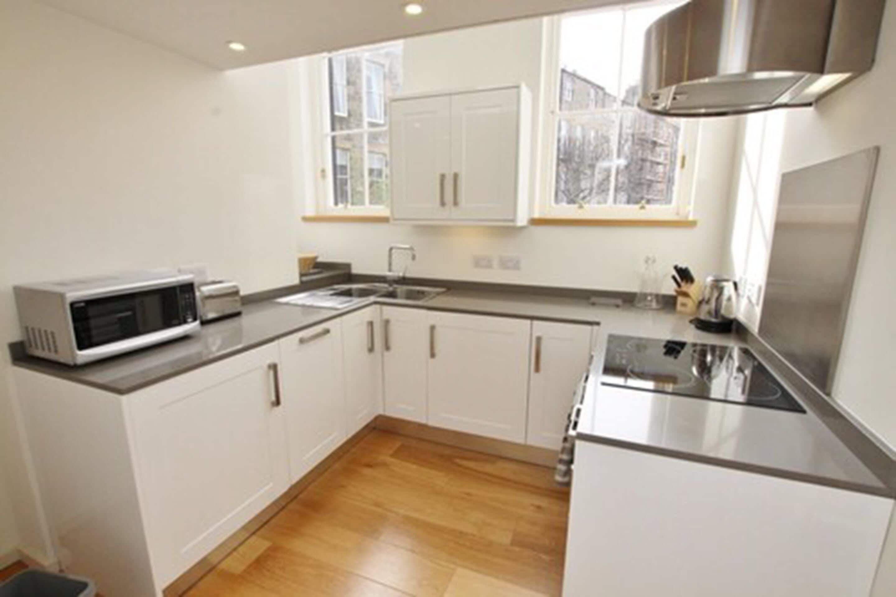 A modern kitchen with white cabinets, a microwave, a sink, and a stove.