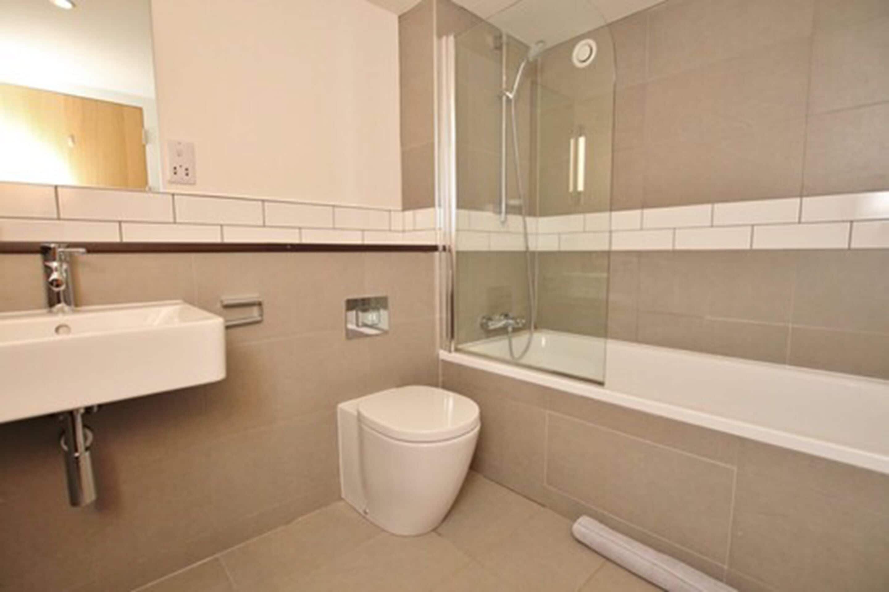 Une salle de bain moderne avec une douche à parois de verre, un lavabo blanc et des toilettes.