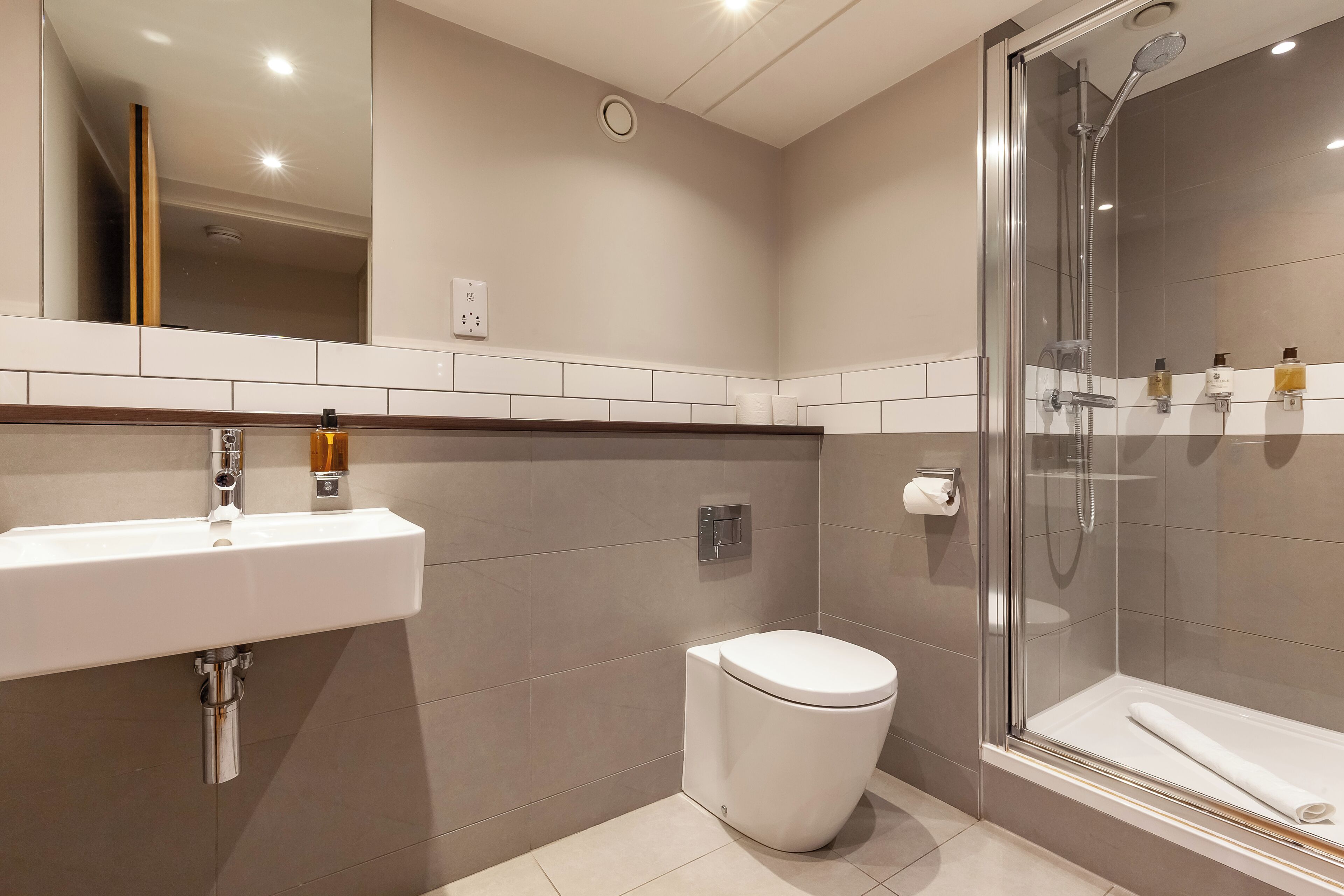 A modern bathroom with a white sink, toilet, and glass-enclosed shower.