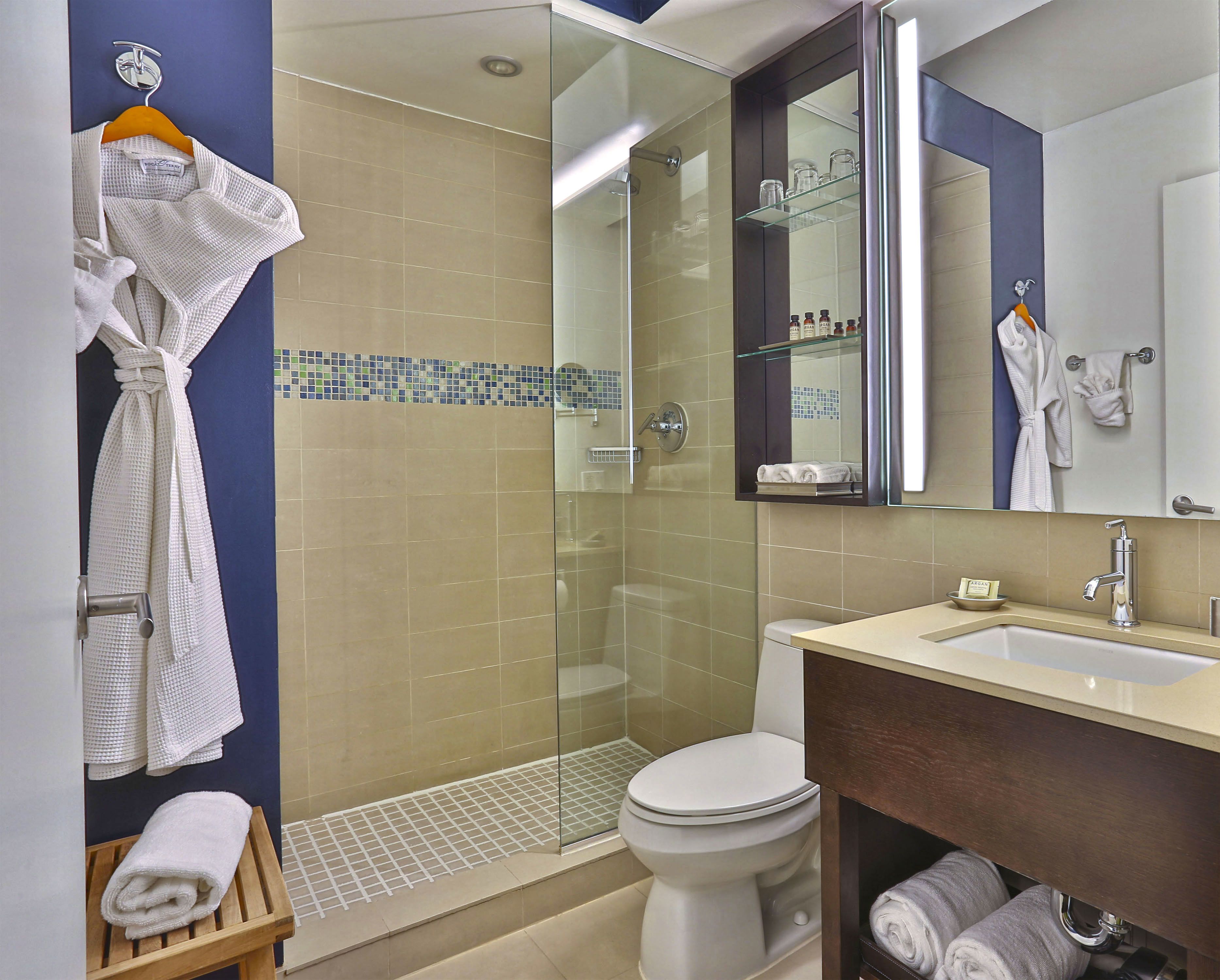 Un baño moderno con cabina de ducha de vidrio, inodoro, lavabo y espejo sobre el lavabo.