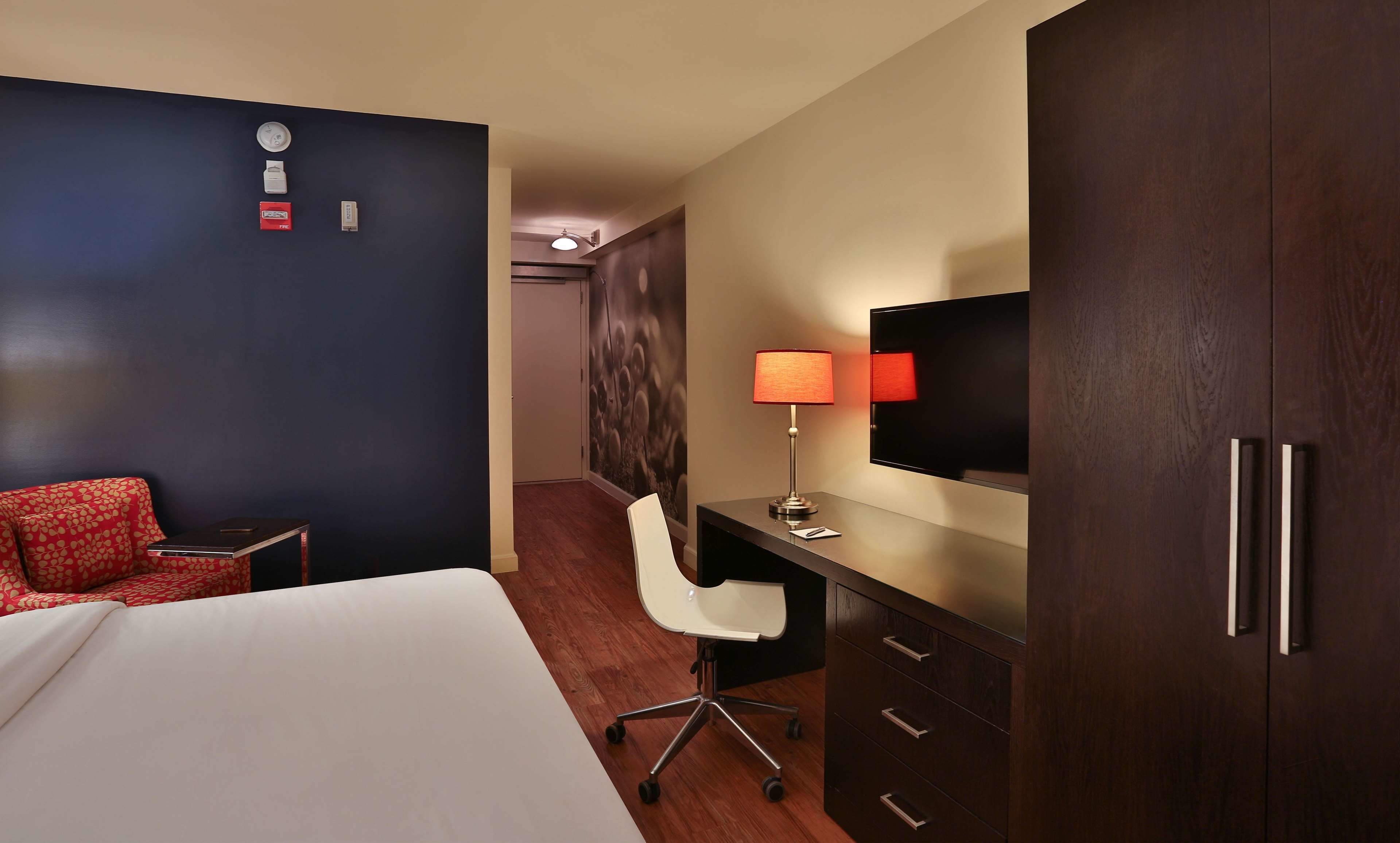 Une chambre d’hôtel comprenant un lit, un bureau avec une chaise, une télévision et une armoire.