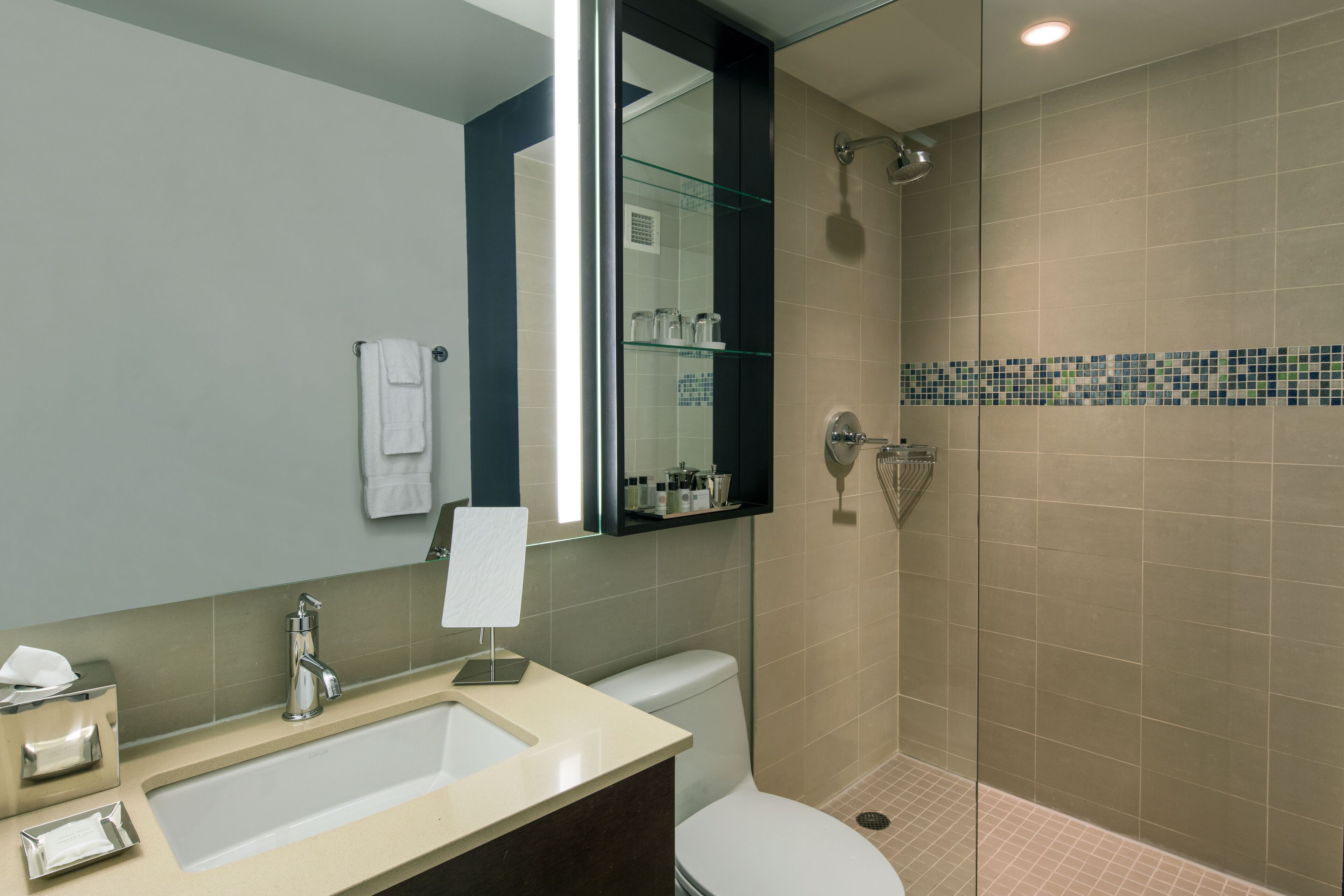A modern bathroom with a sink, mirror, and glass-enclosed shower.