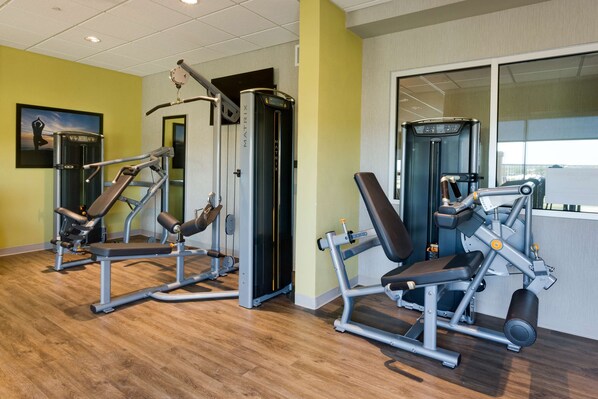 Un gimnasio con equipo de ejercicio, suelo de madera y un cuadro en la pared.