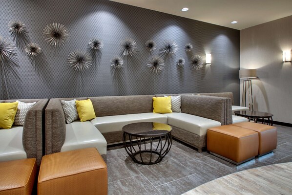 A modern living room with a sectional sofa, a round coffee table, and decorative wall art. - Drury Plaza Hotel Cape Girardeau Conference Center (Cape Girardeau)