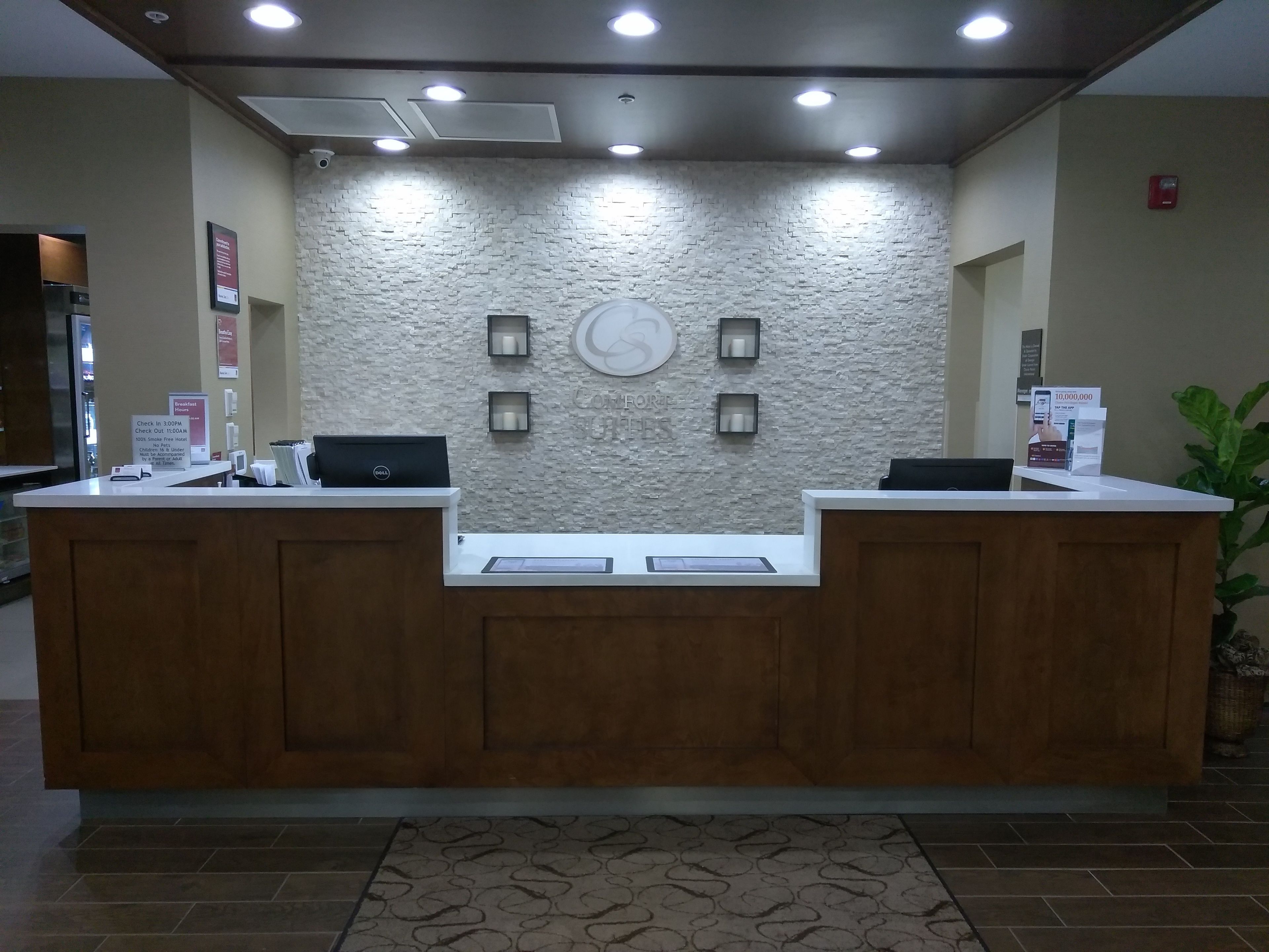 A reception desk with a stone wall backdrop, two computer monitors, and a digital screen.