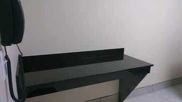 A black desk with a telephone mounted on the wall beside it.