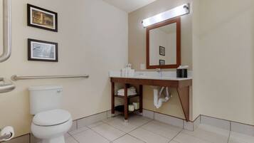Une salle de bain équipée de toilettes, d’un lavabo, d’un miroir et de tableaux encadrés accrochés au mur.