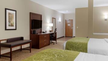 A hotel room with two beds, a desk with a chair, a television, and a framed picture on the wall.