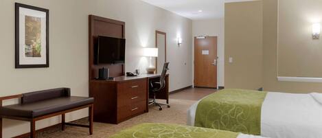 A hotel room with two beds, a desk with a chair, a television, and a framed picture on the wall.