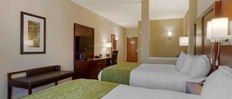 A hotel room with two beds, a desk, a chair, a mirror, and a framed picture on the wall.