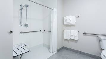 Un baño moderno con cabina de ducha, barras de apoyo, inodoro y toallero.