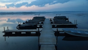 A wooden pier extending into calm water with several boats docked at the end.