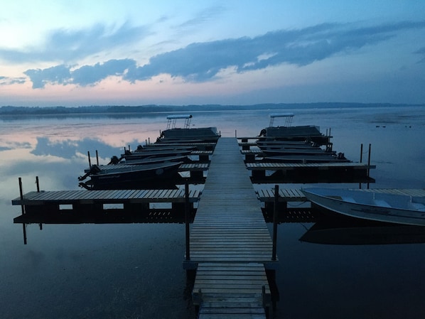 A wooden pier extending into calm water with several boats docked at the end.