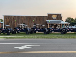 A row of Polaris ATVs parked in front of a wooden building with a sign that reads "TRAILHEAD Adventure.com".