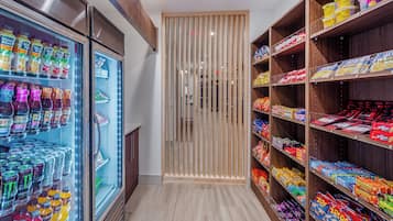 Un pasillo de tienda con bebidas refrigeradas y estantes de aperitivos.