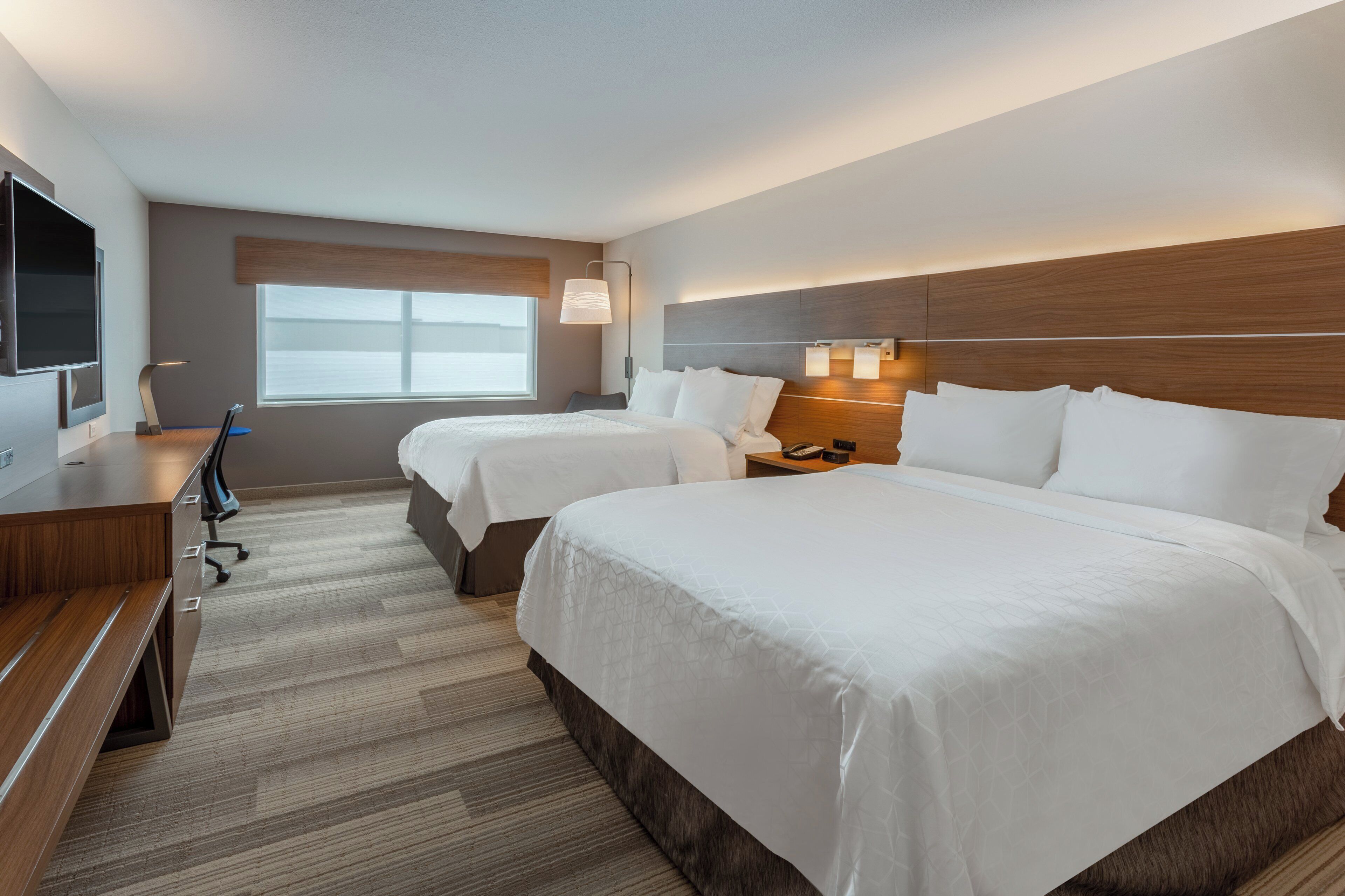 Une chambre d’hôtel avec deux lits, un bureau, une télévision et une fenêtre.