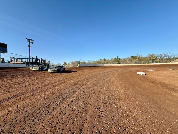 A dirt track with two racing cars and a crowd of people. - Holiday Inn Express & Suites Rice Lake by IHG (Rice Lake)