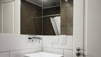 Un baño moderno con un lavamanos blanco, un espejo, una ducha y un inodoro.