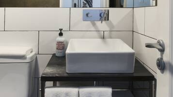 Une salle de bain moderne avec un lavabo blanc, un miroir et un porte-serviettes.