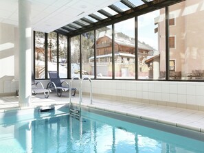 A swimming pool with a view of a mountain cabin through large windows. - Sunny Alps Apartment (La Salle les Alpes)