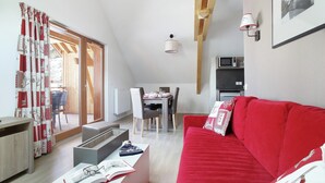 Een moderne woonruimte met een rode bank, een eethoek en een keuken.