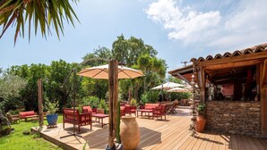 A wooden deck with outdoor furniture, umbrellas, and potted plants. - Villa in Poggio-Mezzana by the Beach (Poggio Mezzana)