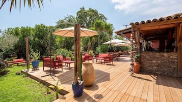 Een houten terras met buitenmeubilair, parasols en plantenpotten.