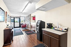 Un vestíbulo de hotel con una recepción, una máquina de café y un quiosco de autoservicio.