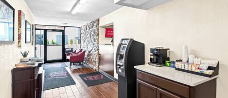 A hotel lobby with a reception desk, a coffee machine, and a self-service kiosk.